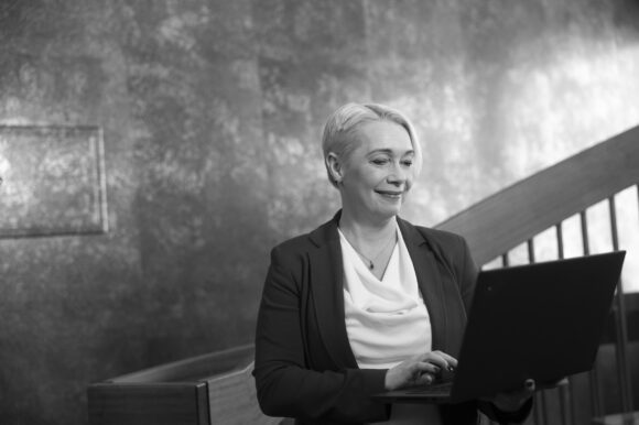 Ragnheiður Birna Björnsdóttir, mynd tekin inni á stigagangi þar sem hún er að vinna í ferðatölvunni standandi